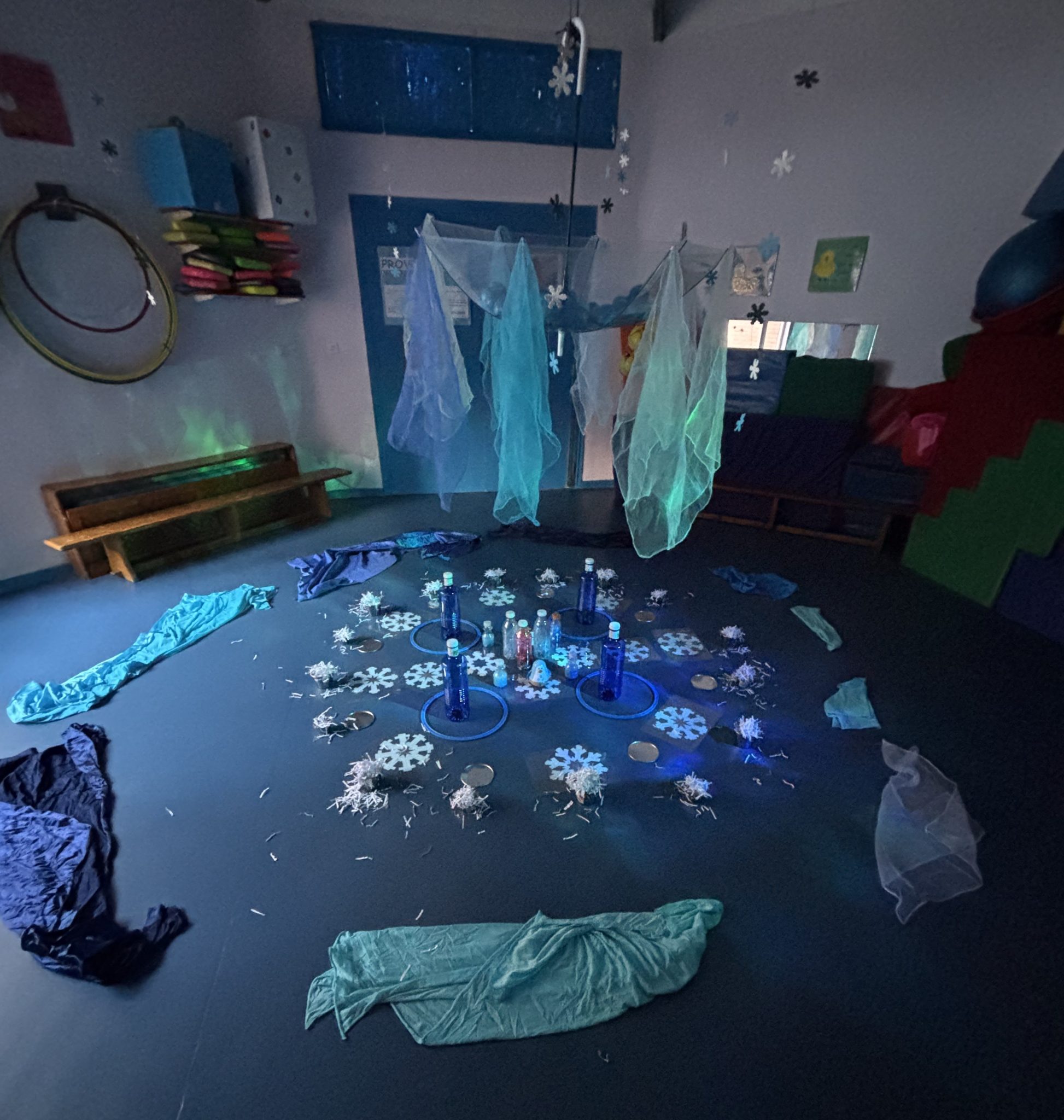 Aula de la escuela infantil decorada con motivos invernales y materiales en el suelo.